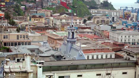 Top-of-the-chilean-national-navy-building-in-the-port-sector-of-Valparaiso-with-seagulls-flying-around-it,-slow-motion