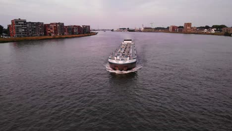 Vista-Aérea-De-Seguimiento-Frontal-De-La-Barcaza-Del-Tanque-De-Carga-Navegando-A-Lo-Largo-Del-Canal-Del-Río-En-Dordrecht,-Países-Bajos,-Tráfico-Náutico-Y-Navegación-Marítima-Costera