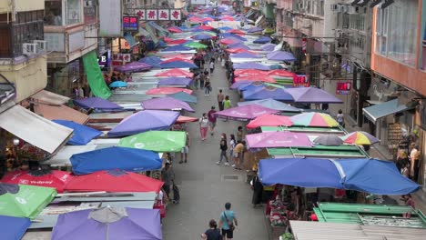 Shoppers,-walk-through-the-Fa-Yuen-street-outdoor-market-stalls-selling-vegetables,-fruits,-gifts,-and-fashion-goods-in-Hong-Kong