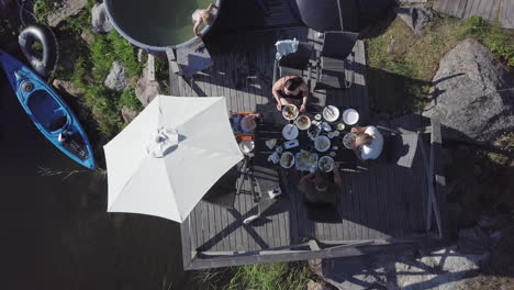 Summer-vacation-in-Scandinavia,-aerial-top-down-view-of-People-eating-at-Nordic-cabin