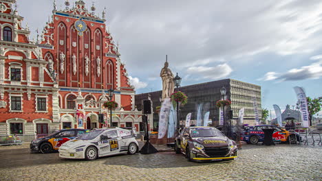 Toma-De-Autos-De-Carrera-Del-Campeonato-Mundial-De-Carreras-Cruzadas-Rx-Están-En-Exhibición-En-Un-Día-Nublado-En-Un-Lapso-De-Tiempo-Frente-A-Una-Antigua-Estructura-Histórica