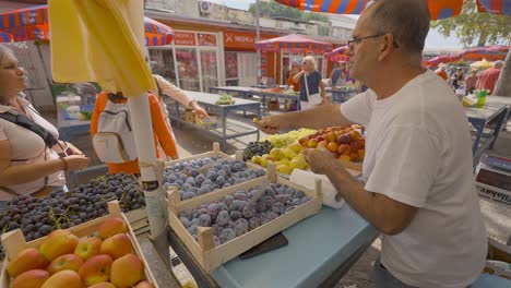 Tipo-En-El-Puesto-De-Frutas-Ofreciendo-Muestras-De-Sus-Duraznos-A-La-Gente