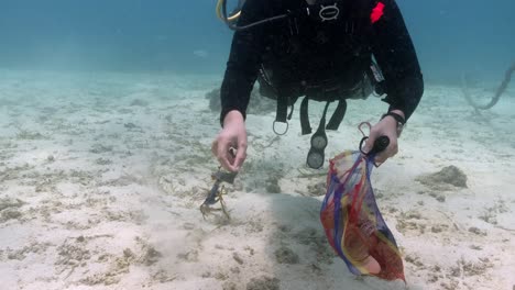 Taucher,-Der-Während-Der-Ozeanreinigung-Verschmutzten-Müll-Auf-Sandboden-Sammelt