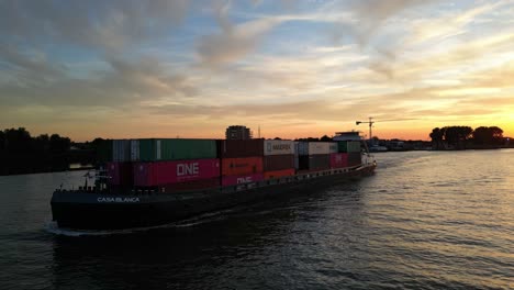 Barco-Portacontenedores-Casa-Blanca-Navegando-Durante-El-Atardecer-Cerca-De-Zwijndrecht,-Países-Bajos-Occidentales