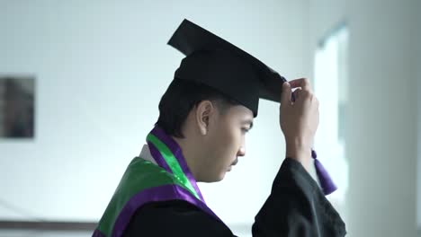 El-Graduado-Masculino-Limpia-Las-Correas-De-Su-Gorra-De-Graduación-Y-Luego-Posa-Para-La-Cámara,-Preparándose-Para-Asistir-A-La-Ceremonia-De-Graduación-En-El-Campus