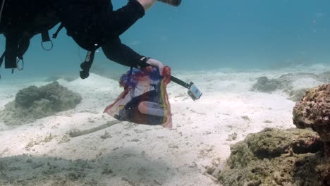 Divertido-Buzo-Voluntario-Recoge-Una-Botella-De-Cerveza-Vacía-En-El-Fondo-Del-Mar-Durante-La-Limpieza