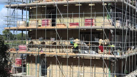 Timelapse-at-construction-site-with-brick-layer-building-the-outer-exterior-facade-and-clouds-passing-by-behind