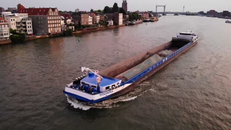 Cargo-ship-carrying-sand-through-dutch-canal-during-golden-hour