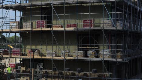 Nahaufnahmezeitraffer-Auf-Der-Baustelle-Mit-Arbeitern,-Die-Ziegelsteine-Bewegen,-Um-Den-Bau-Der-Außenfassade-Eines-Wohnhauses-Vorzubereiten