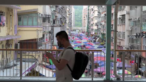 A-daily-life-scene-of-Chinese-pedestrians-walking-through-a-pedestrian-bridge-as-an-outdoor-street-market-is-seen-in-the-background-in-Hong-Kong