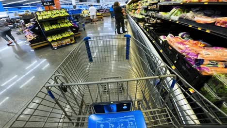 Punto-De-Vista-Mientras-Empuja-Un-Carrito-A-Través-De-La-Sección-De-Productos-Y-Fuera-De-Walmart