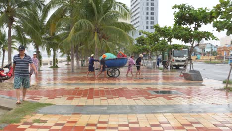 People-Relocating-Small-Boat-From-the-Sea-Coast-on-Coastal-Road-Ahead-of-Tropical-Typhoon,-Da-Nang-City,-Vietnam