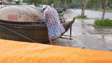 Hombre-Asegurando-Su-Bote-Junto-A-La-Carretera-Frente-A-La-Costa-Del-Mar-Antes-De-Que-La-Tormenta-Golpee-El-Continente,-La-Ciudad-De-Da-Nang,-Vietnam