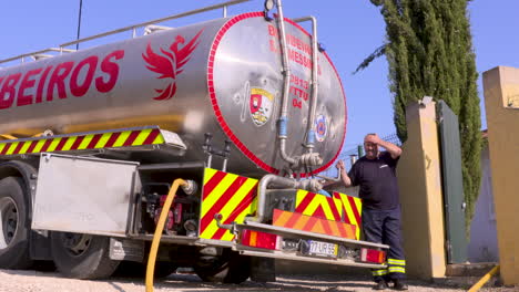 Aufnahmen-Eines-Feuerwehrmanns-Und-Des-Feuerwehrautos,-Die-Während-Der-Dürre-Der-Globalen-Erwärmung-Kommen,-Um-Die-Ausgetrocknete-Wasserversorgung-Eines-Hauses-Wieder-Aufzufüllen