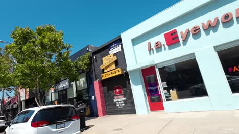 Angled-POV-View-Driving-Past-Store-Fronts-Along-Melrose-Avenue-On-Sunny-Day