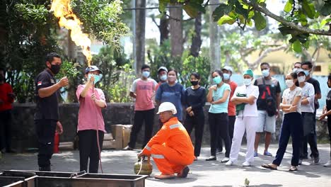 Yogyakarta,-Indonesia---Sep-24,-2022-:-Asian-young-woman-practicing-how-to-extinguish-a-fire-on-a-gas-stove-leak-in-the-yard