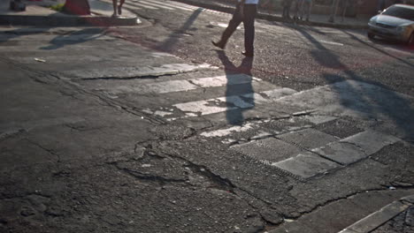 Pedestrians-and-cars-cross-a-crackled-and-damaged-asphalt-street-during-the-afternoon-in-Santa-Ana,-El-Salvador