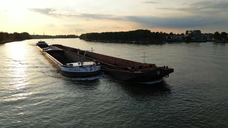 Aerial-Parallax-Around-Forward-Bow-Of-Amoureus-Push-Freighter-Sailing-Along-Beneden-Merwede-During-Sunset