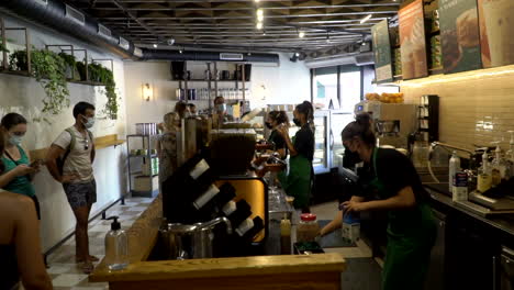 Leute-Mit-Gesichtsmasken,-Die-In-Der-Schlange-Stehen,-Um-Ihren-Morgenkaffee-Bei-Starbucks-Zu-Bekommen