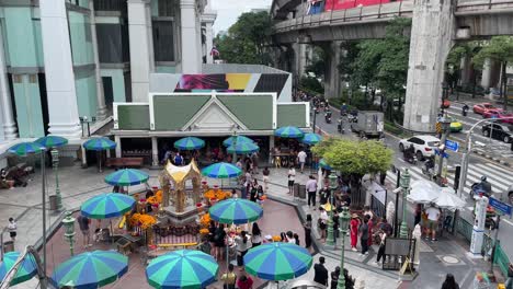 Ein-Schwenkblick-Auf-Den-Sich-Bewegenden-Bts-Sky-Train-Mit-Verkehrsfluss-Zum-Berühmten-Erawan-schrein-An-Der-Ratchaprasong-kreuzung-Auf-Der-Ratchadamri-Road-In-Bangkok,-Thailand