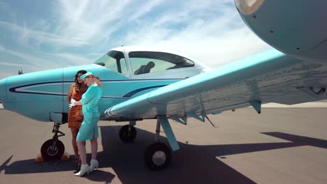 Dos-Modelos-Femeninas-Posando-Junto-Al-Clásico-Avión-Vintage-De-Color-Verde-Azulado