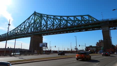 Tráfico-De-Automóviles-Y-Autobuses-Bajo-El-Puente-De-Acero-Jacques-Cartier-Ciudad-De-Montreal-Canadá,-Estructura-Elevada-Metálica-Rígida-Urbana-Para-Transporte,-Infraestructura-Arquitectónica-E-Ingeniería