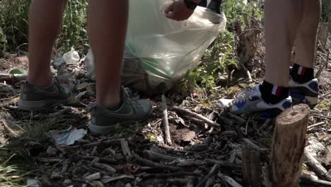 Toma-De-Vista-De-Cultivo-De-Un-Adolescente-Y-Un-Padre-Recogiendo-Basura-En-Una-Calle-Y-Llenando-Una-Bolsa-De-Plástico-En-Milán,-Italia