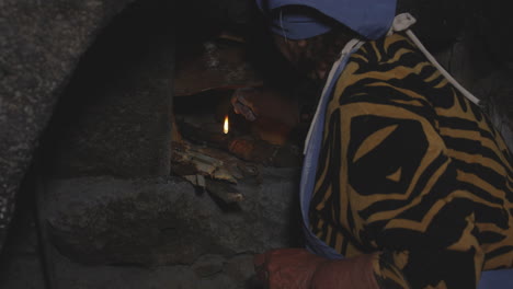 Female-Cook-Igniting-Firewood-In-Traditional-Stove-For-Cooking-In-Georgia