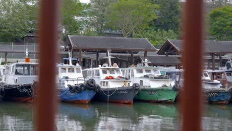 Mirando-A-Través-De-Las-Parrillas-De-Metal-Con-Bumboats-Amarrados-En-El-Embarcadero-De-La-Aldea-De-Changi-En-El-Fondo-En-Singapur