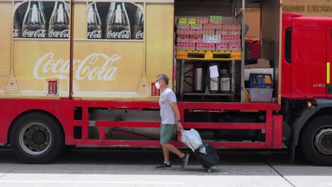 Ein-Mann-Geht-An-Einem-Coca-Cola-Lieferwagen-Vorbei,-Während-Waren-Der-Softdrink-Marke-An-Restaurants-Und-Andere-Kunden-In-Der-Nähe-Verladen-Werden