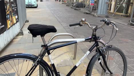 Panning-view-over-bicycle-locked-to-rack,-looking-down-Whitefriargate,-City-of-Hull,-buildings-clad-in-scaffold