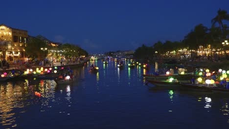 Amplia-Toma-Nocturna-Sobre-El-Tranquilo-Río-Hoai-Que-Atraviesa-Hoi-An-Ciudad-Antigua---Barcos-Tradicionales-Con-Farolillos-Coloridos-Que-Llevan-A-Los-Turistas-A-Dar-Paseos