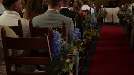 Ceremonia-De-Boda-Con-Invitados-Sentados-En-Una-Silla-De-Madera-Decorada-Dentro-De-La-Capilla