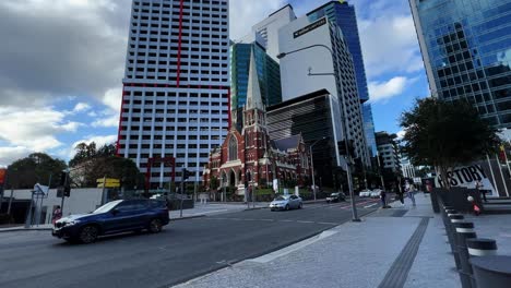 Wide-angle-shot-of-a-heritage-listed-Victorian-Gothic-Revival-architecture,-Albert-street-uniting-church-at-the-corner-of-Ann-street-with-contrast-modern-high-rise-buildings-in-the-background