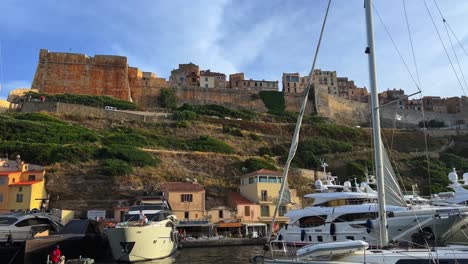 Puerto-De-Bonifacio-Con-Yates-Amarrados-Y-Ciudadela-Del-Castillo-Encaramado-En-Un-Acantilado-Visto-Desde-Un-Barco-Turístico-En-Movimiento,-Isla-De-Córcega-En-Francia