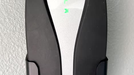 Close-up-on-TESLA-super-charger-plug-with-glowing-logo-installed-inside-modern-garage