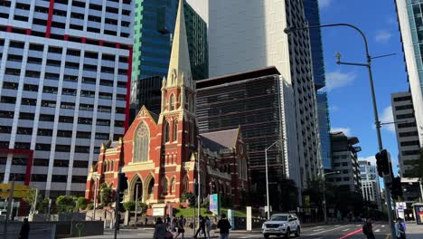 Static-shot-of-a-heritage-listed-Victorian-Gothic-Revival-architecture,-Albert-street-uniting-church-at-the-corner-of-Ann-street-with-pedestrians-crossing-the-street