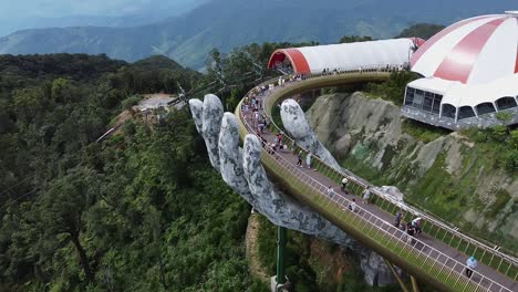 Vista-Aérea-De-Personas-Caminando-Por-El-Puente-De-Mano-Gigante-En-La-Cima-De-La-Montaña-Nui-Chua,-Colinas-Ba-Na,-Da-Nang