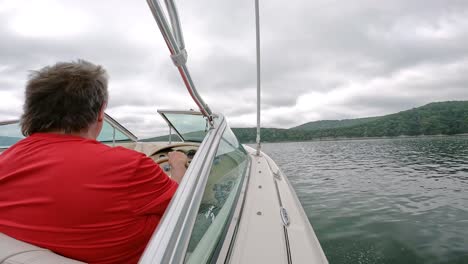 La-Parte-Trasera-Del-Hombre-Con-Camisa-Roja-Conduciendo-Un-Barco-Deportivo-Navegando-En-El-Lago-Table-Rock-En-Las-Montañas-Ozark-En-Missouri,-Ee.uu.-En-Un-Día-Nublado