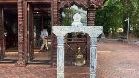 Bronzeglocke-Läutet-Und-Schwingt-Vor-Dem-Haupteingang-Des-Dreistöckigen-Gebäudes-Mit-Hohem-Kulturerbe-Nepalesische-Pagode,-Parkanlagen,-South-Bank-Brisbane-City