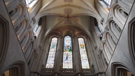 Wells-Cathedral-ceiling-arches,-camera-moving-down-from-the-ceiling-showing-the-tainted-glass-windows