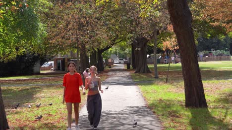 Un-Par-De-Chicas-Caminando-Por-El-Verde-De-Wanstead-A-La-Sombra-De-Los-árboles