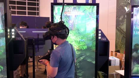 Ein-Junger-Chinesischer-Spieler-Spielt-Ein-Virtual-reality-shooting-videospiel,-Während-Er-Sich-Umdreht,-Um-Während-Des-Hong-Kong-Computer-And-Communication-Festival-In-Hong-Kong-Ein-Ziel-Zu-Finden