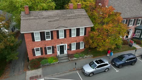 Pedestrians-walk-on-sidewalk-in-quiet-historical-neighborhood-during-fall