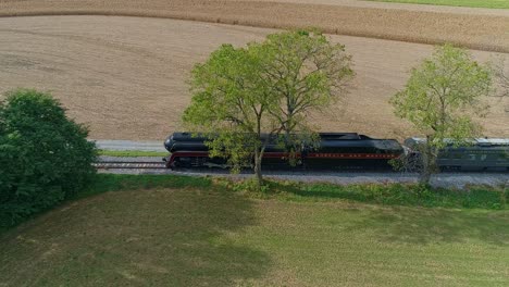 Ronks,-Pennsylvania,-September-25,-2021---Drone-Side-View-of-a-Steam-Locomotive-Traveling-on-a-Single-Track-Thru-Farmlands,-Blowing-Smoke