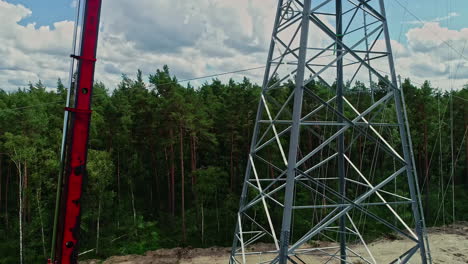 Tilt-down-shot-of-workers-using-crane-to-install-power-pole-for-placing-power-lines-pylon-at-daytime