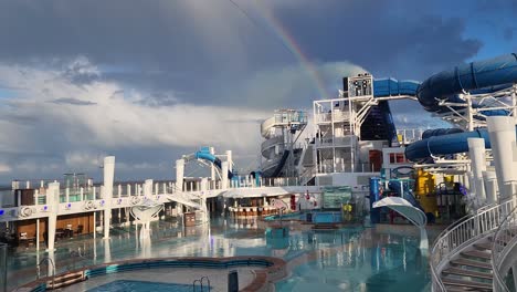 Ncl,-Norwegian-Bliss-Kreuzfahrtschiff-Pooldeck-Nach-Regen-Mit-Schornstein-Und-Regenbogen