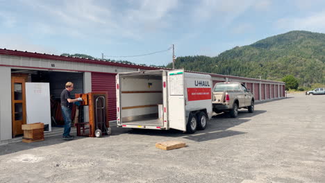 Man-using-a-dolly-to-load-a-desk-onto-a-U-Haul-trailer