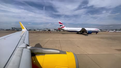 Vista-Del-Ala-De-Un-Avión-Amarillo-Y-El-Motor-De-Rodadura-En-El-Aeropuerto-Británico-Gatwick-De-Londres-En-El-Reino-Unido