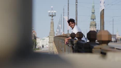 Elegante-Viajero-Indio-Disfruta-De-La-Belleza-Del-Centro-Y-El-Puente-De-Riga,-Vista-Lateral